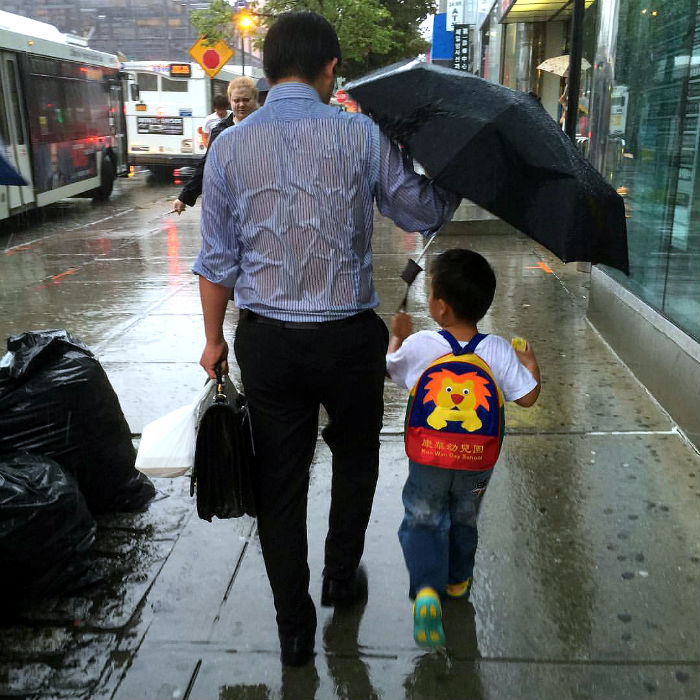 daddy drench rain holding umbrella to son viral photo