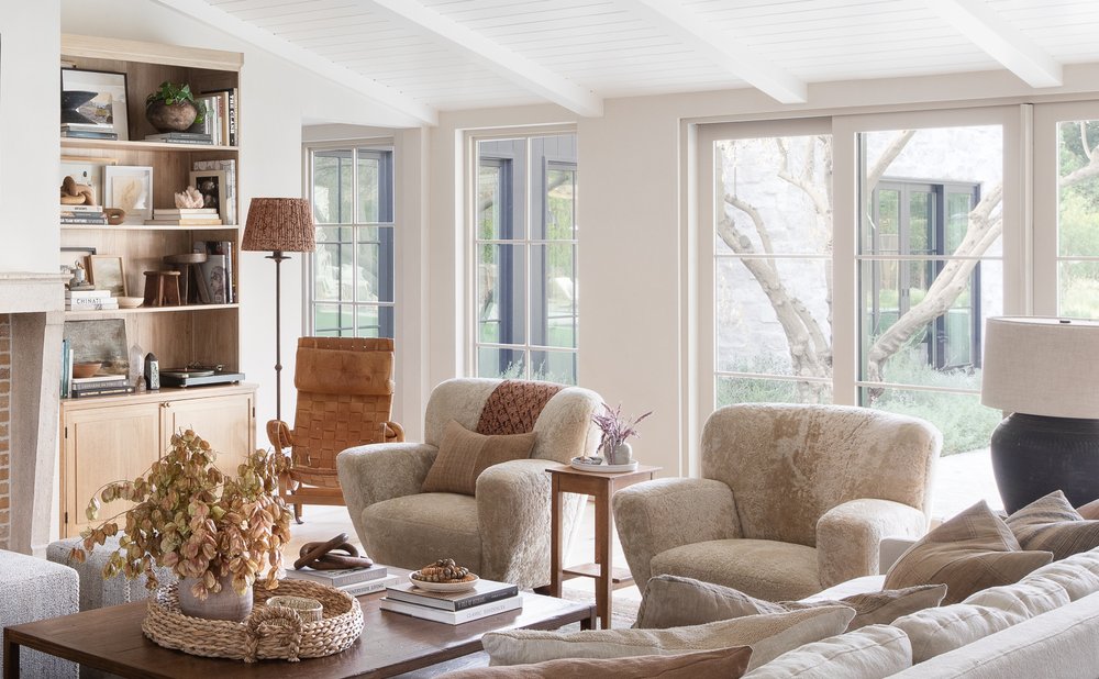 Layered neutral living room with textured chairs, wool rug and linen pillows