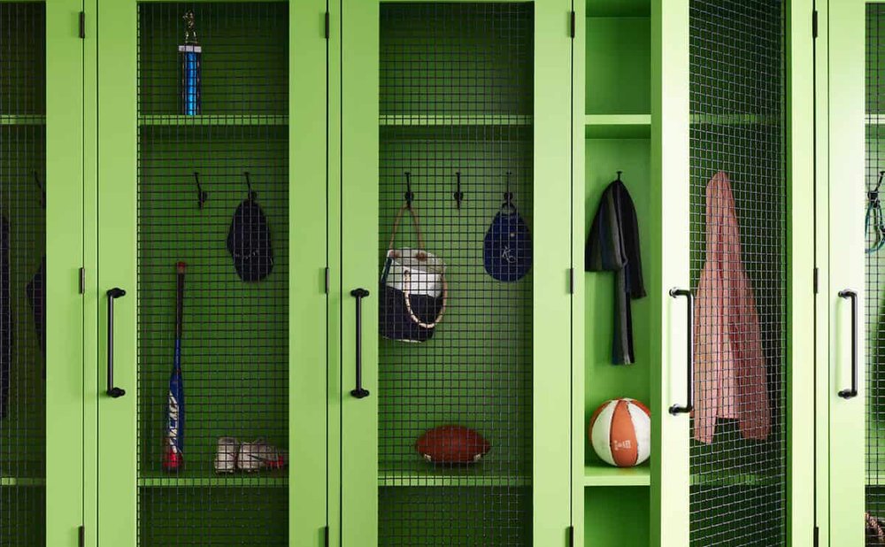 Floor-to-ceiling mudroom lockers in a soft green paint with a bench seat in each bay