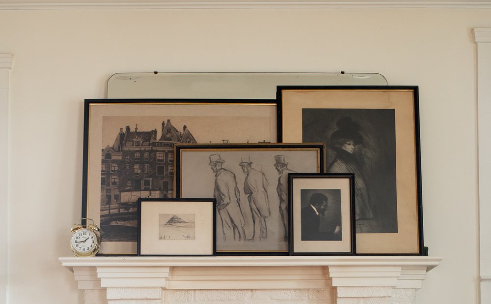 Mantel decor with layered framed art leaning against the wall