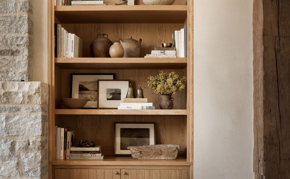 Built-in oak shelves styled with books and pottery