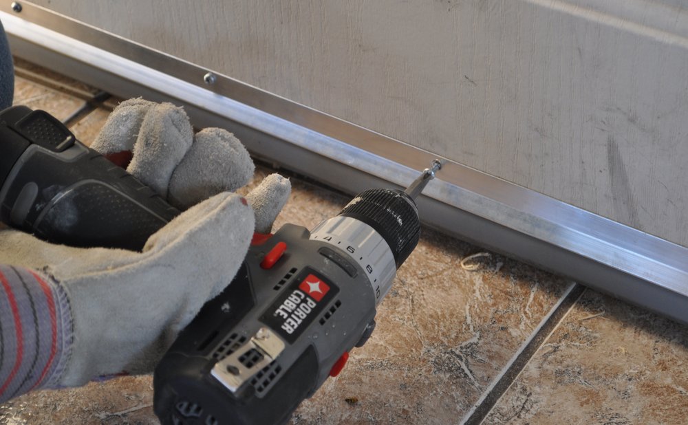 Door sweep screwed to the bottom of an exterior door to stop drafts under doors