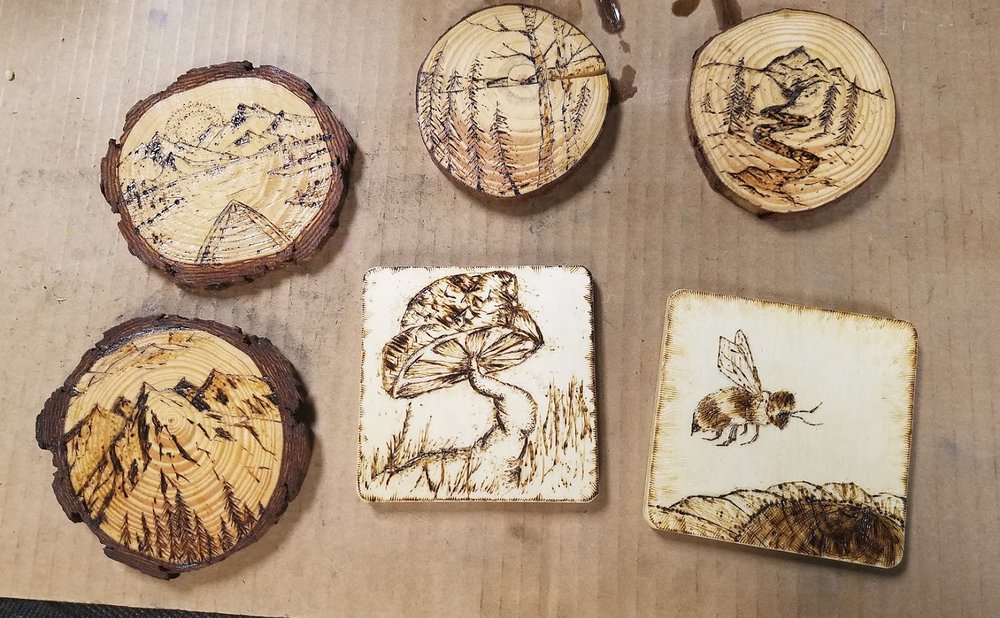 Set of wood-burned coasters with leaf designs on a table