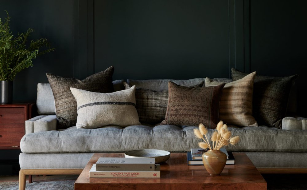 Moody dark-painted living room with a grey sofa and burl coffee table