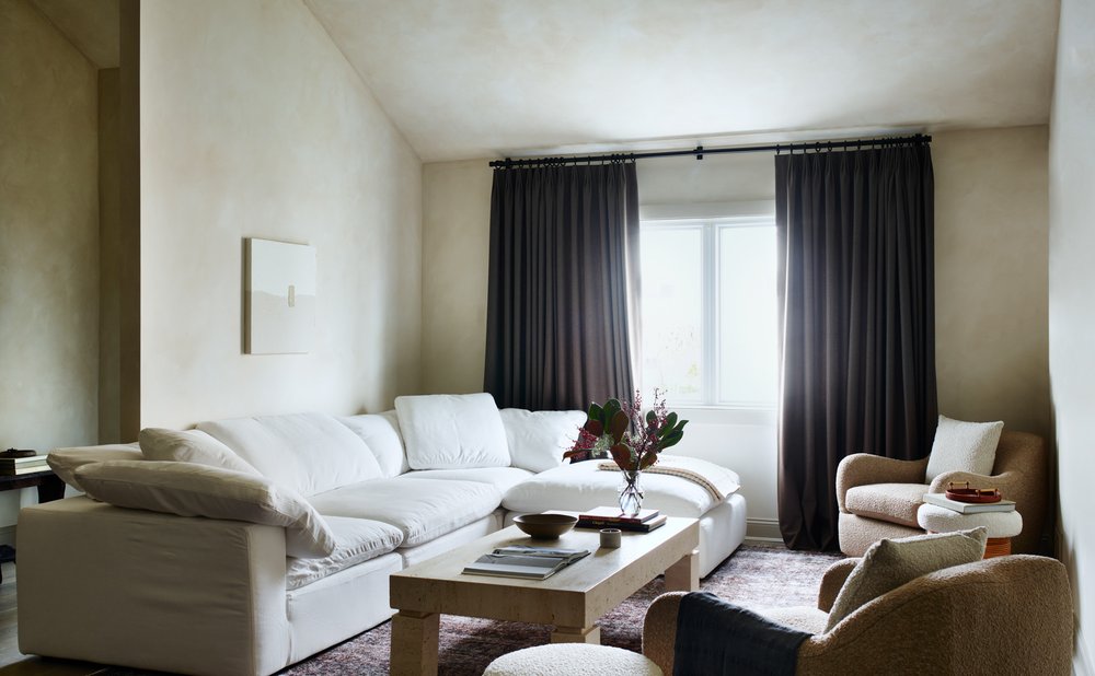 Plaster-look walls in warm beige around a white sofa and wood coffee table