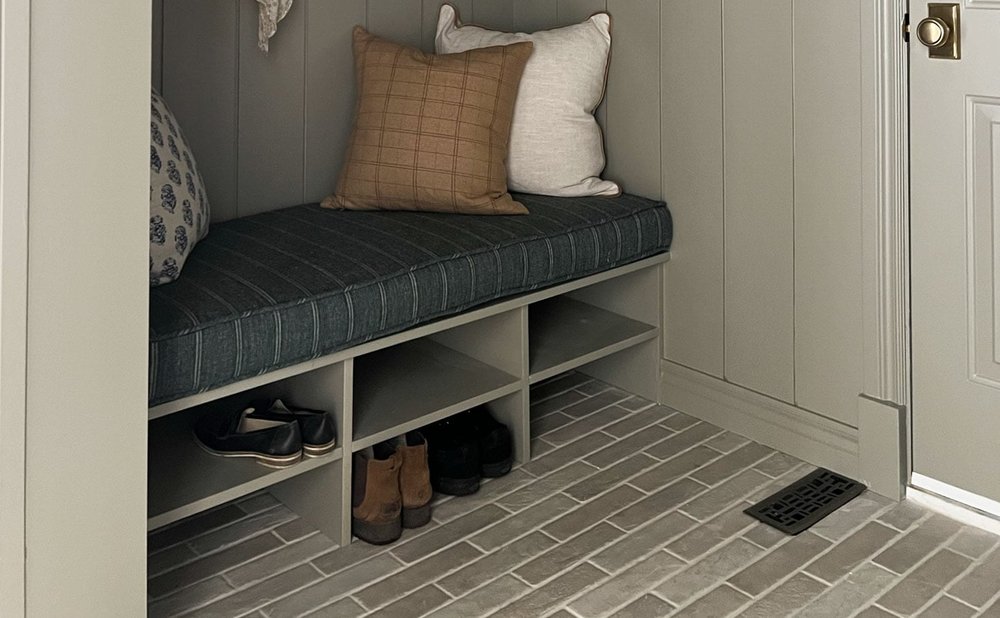 Mudroom with brick-look tile floor under a built-in bench with boots in cubbies