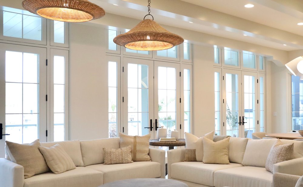 Woven rattan pendants over a living room seating area with a round ottoman