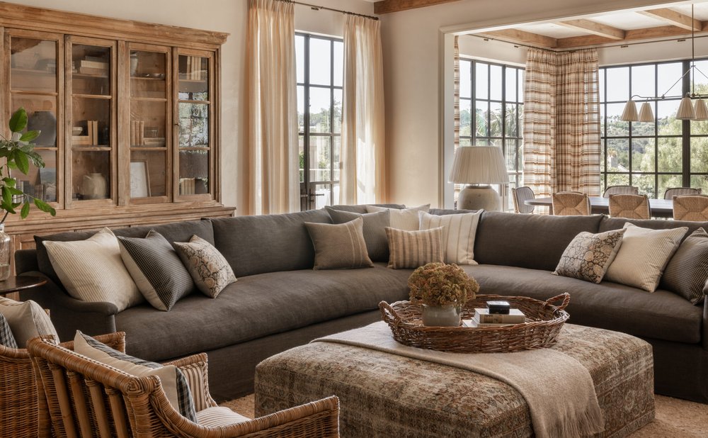 Charcoal sectional with warm pillows, rattan chair and wood cabinet