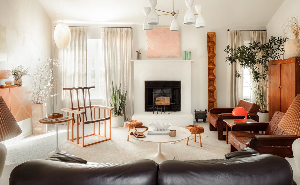 Black leather sofa in a bright plaster living room with rust accent chairs