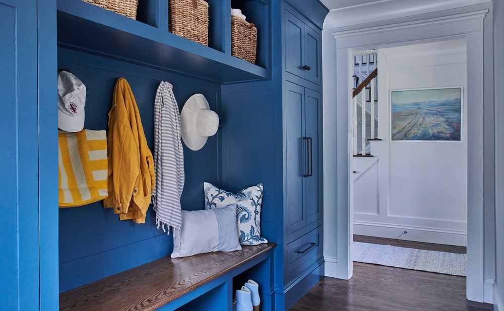 Mudroom cabinets and trim painted a bold navy blue with brass hooks