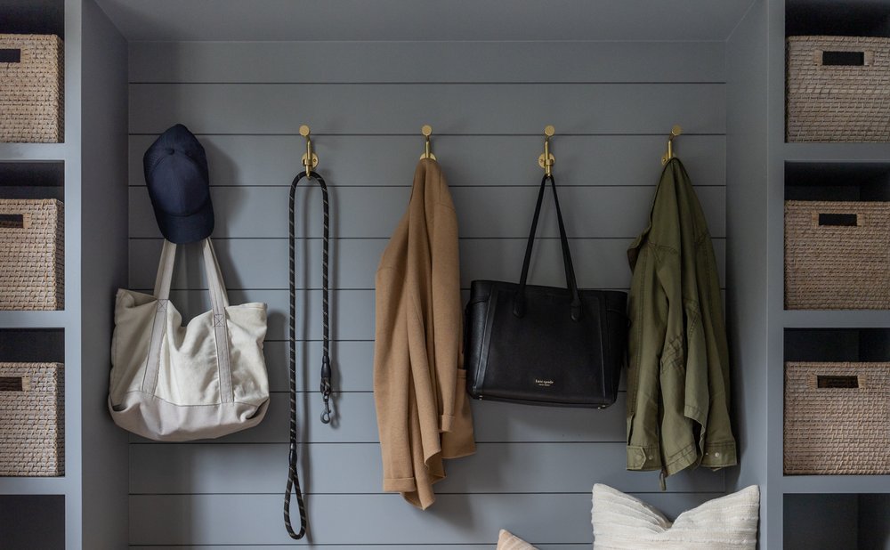 Mudroom storage with open cubbies holding woven baskets with name labels
