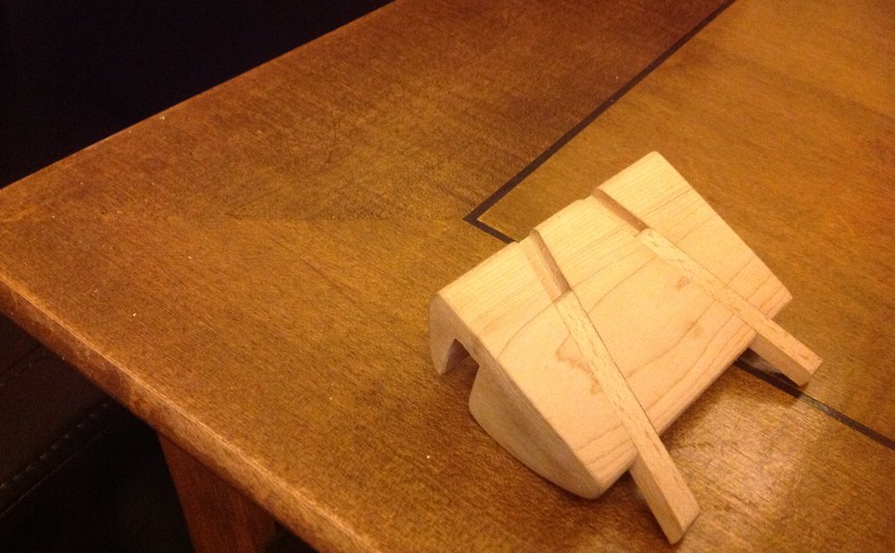 Wooden phone and tablet stand made from a hardwood scrap on a desk