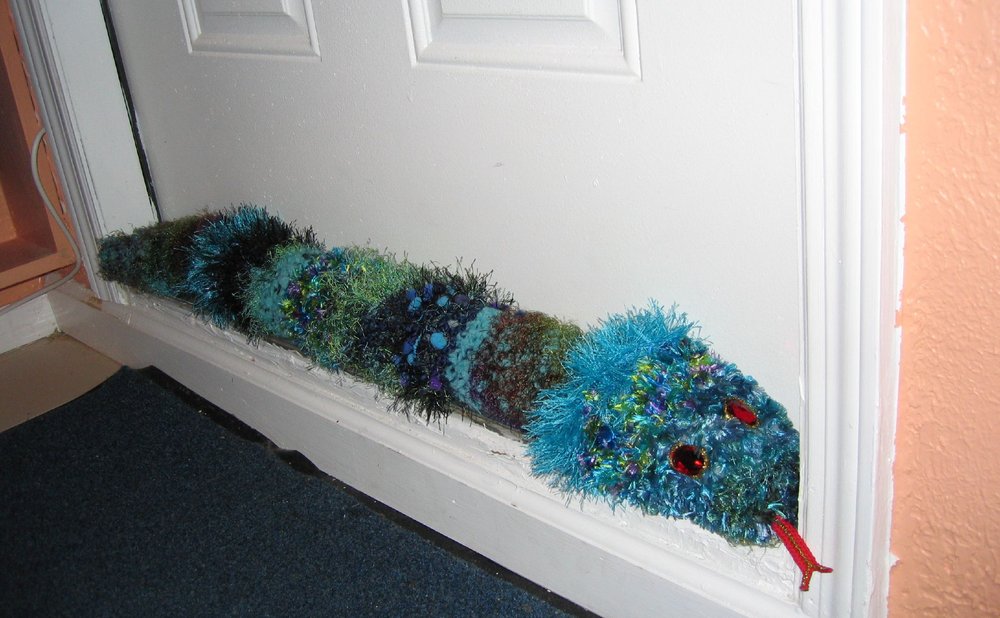 Fabric draft stopper lying along the bottom of a door you rarely open