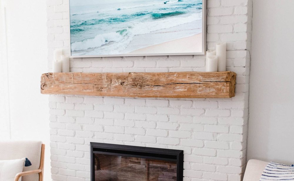 Modern farmhouse mantel made from a reclaimed wood beam over a white brick fireplace