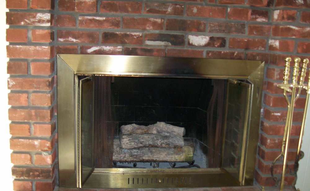 Hand closing a fireplace damper to stop drafts when the fireplace is not in use