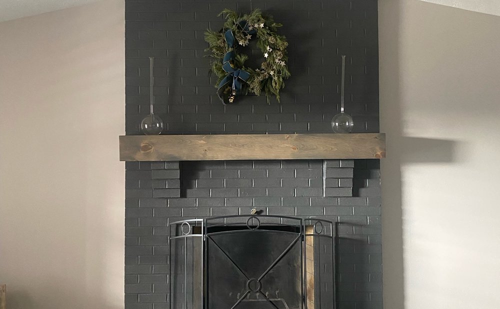 Painted brick fireplace in gray with a simple wood mantel