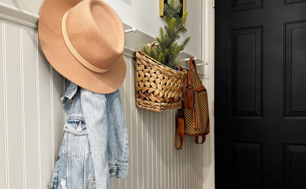 Shaker-style wooden peg rail in a mudroom holding hats, a tote bag and a dog leash