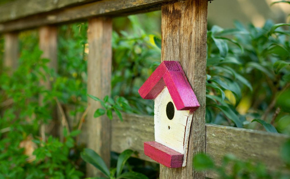 Scrap wood birdhouse mounted on a post in a garden