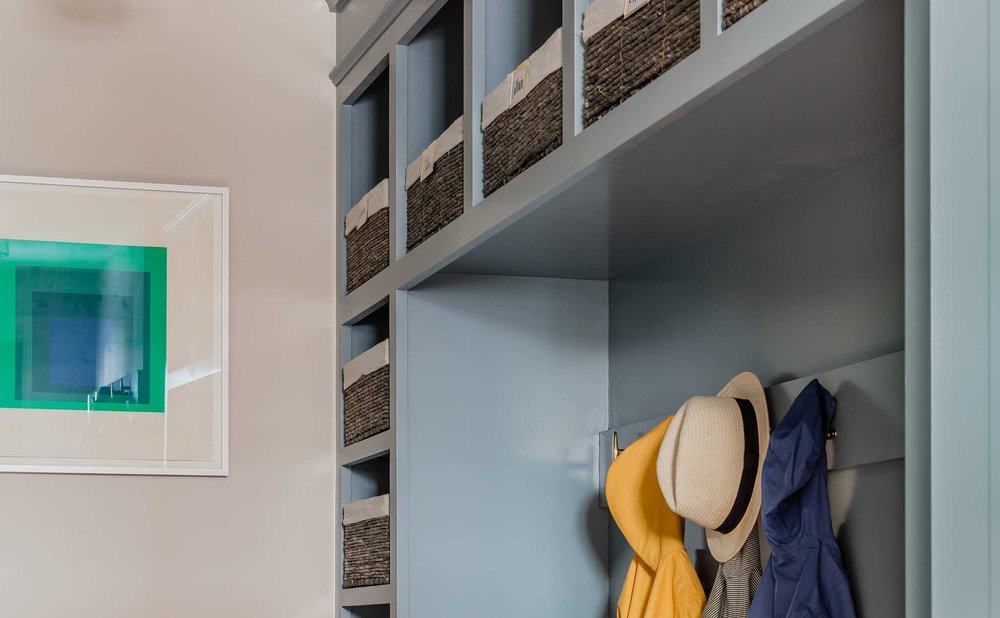 Overhead mudroom shelving with bins for off-season gear above coat hooks