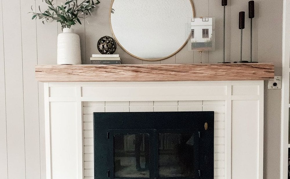 Floating wood mantel shelf on a plain white fireplace surround