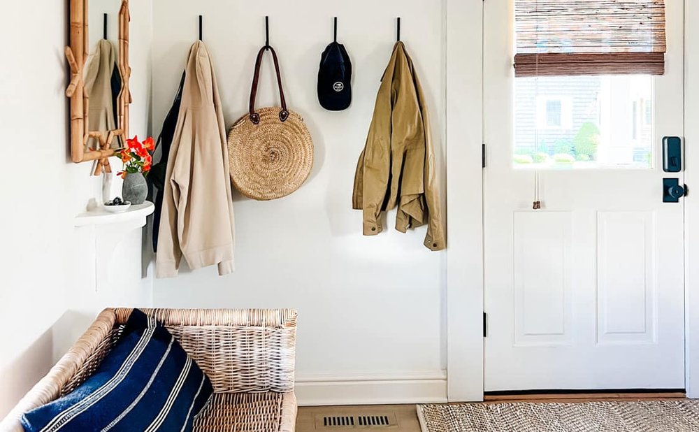 Entryway bench mudroom with a freestanding bench, wall hooks and a round mirror