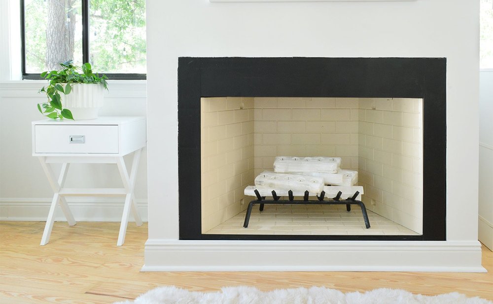 Modern fireplace without a mantel, with a slim black surround and a plant on a side table