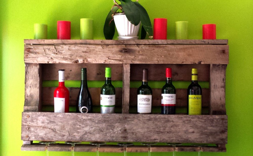 Wall-mounted wine rack made from scrap wood boards holding bottles