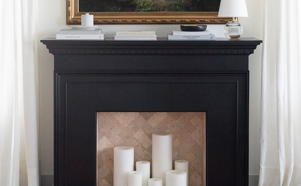 Faux fireplace mantel filled with pillar candles and art above