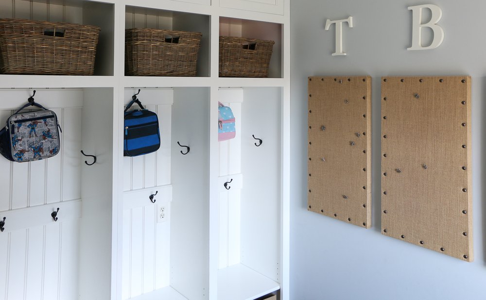 Kid-height hooks in a mudroom holding small backpacks and jackets below adult hooks
