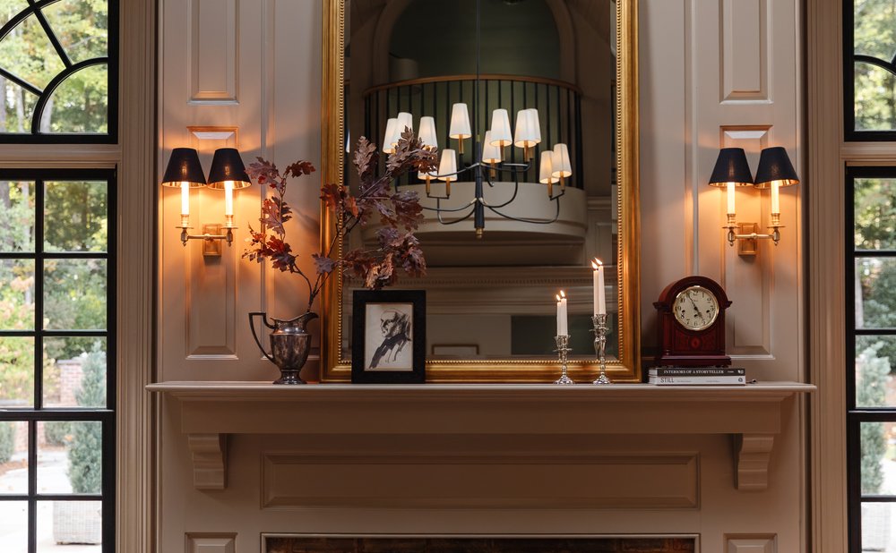Asymmetrical mantel arrangement with branches and art on one side and candlesticks on the other