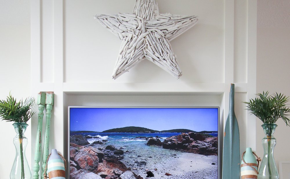 Coastal mantel with a driftwood star, painted buoys and soft blue glass vases